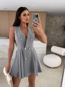 Détail d'une robe grise sans manches à col en V avec boutons dorés et jupe plissée chic