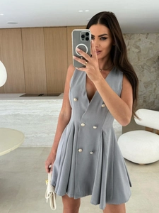 Détail d'une robe courte grise sans manches à col en V avec boutons dorés à double boutonnage