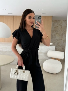 Detail of black V-neck jumpsuit featuring ruffle butterfly sleeves and waist tie belt