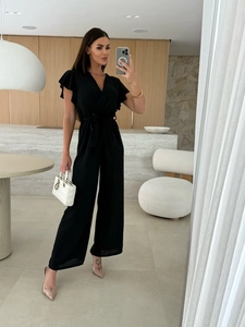 Detail view of the black V-neck jumpsuit featuring ruffle sleeves and a waist-tie design
