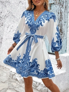 Detailed view of paisley print dress with V-neck, waist tie, and elegant lantern sleeves