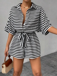 Detail of a striped button-down romper featuring half sleeves and a matching waist tie belt
