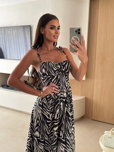 Detail of zebra print dress featuring adjustable shoulder straps and front button decoration