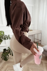 Detail of slim-fit brown faux suede jacket featuring shoulder straps and waist tie design