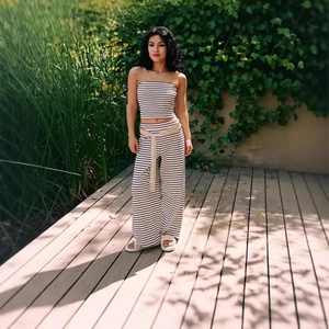 Detail of black and white striped tube top and wide-leg trousers set on a wooden patio