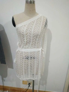 Détail d'une robe en tricot blanche à une épaule avec texture ajourée et ceinture fine