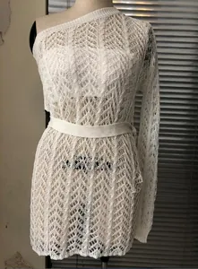 Détail d'une robe en crochet blanc avec épaule dénudée et ceinture à nouer à la taille