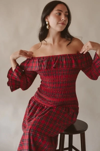 Détail de la robe de Noël à carreaux rouges avec smocks et décolleté à volants épaules nues