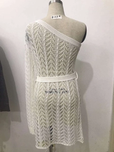 Détail de robe blanche en crochet ajouré avec épaule asymétrique et ceinture assortie