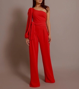 Detail of red one-shoulder jumpsuit featuring a tied waist bow and wide leg cut