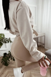 Detail of beige faux suede tracksuit featuring drawstring waist hoodie and slim leggings