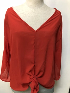 Detail of orange V-neck chiffon blouse featuring a stylish front knot and flutter sleeves