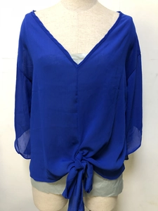 Close-up of the front knot detail on a royal blue V-neck chiffon blouse with loose sleeves