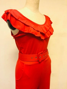 Détail de la combinaison rouge épaules dénudées avec volants et large ceinture assortie