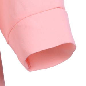Gros plan du poignet en mousseline rose montrant les coutures nettes et la texture