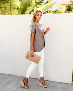 Detail of taupe one-shoulder knit top with side knot and ruched hem detail on model