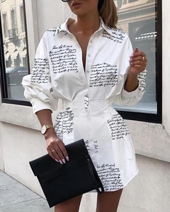 Détail d'une robe chemise blanche à manches longues avec imprimé noir et taille cintrée