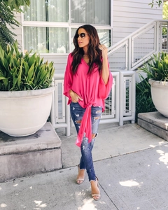 Outdoor shot of a rose red V-neck chiffon shirt with a front knot and blue ripped jeans