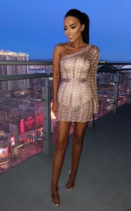 Détail d'une robe à paillettes or rose à une épaule avec texture métal et ceinture