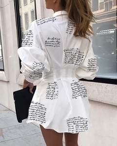 Détail de la robe chemise blanche avec imprimé noir et élégant design plissé à la taille