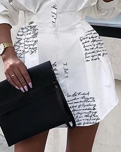 Détails des plis à la taille et imprimé cursif noir sur une robe chemise blanche à manches