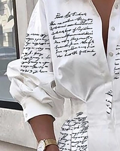 Détail d'une chemise blanche à manches longues avec imprimé cursif noir et poignets boutonnés