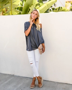 Detail of off-shoulder dark grey top paired with white distressed jeans and wedge sandals