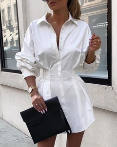 Détail de la taille cintrée et de la fermeture à boutons de cette robe chemise blanche