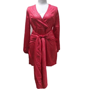 Détail d'une robe rouge à col en V avec pois dorés et ceinture à nouer à la taille