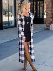 Full-body street view of a black and white buffalo plaid long cardigan with boots