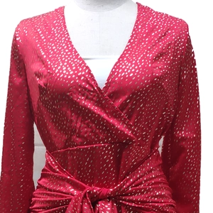 Détail de robe rouge à col en V avec pois dorés, taille croisée et manches lanternes