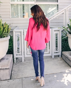 Back view of magenta chiffon V-neck blouse with tiered sleeves and curved hem design