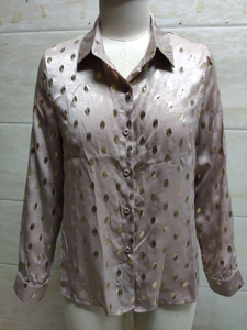 Détail d'un chemisier en satin rose champagne à pois dorés et boutonnage frontal