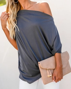 Close-up of charcoal grey one-shoulder top fabric with a matching leather handbag