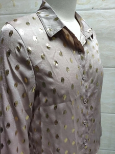 Détail de chemise à manches longues pour femme avec pois dorés métallisés sur fond rose