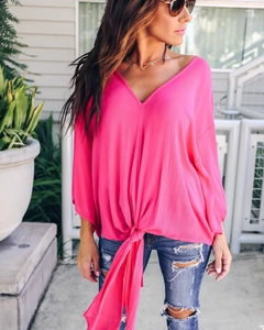 Detail of hot pink V-neck chiffon blouse with stylish front knot and textured fabric