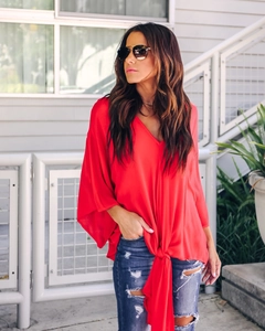 Detail of red V-neck chiffon blouse with ruffle sleeves and stylish front tie knot design