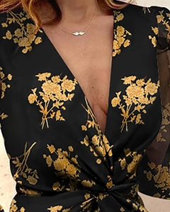 Close-up of deep V-neckline and bright floral print on mesh sleeve midi dress