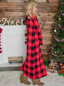 Detailed view of a red and black plaid cardigan in a cozy Christmas fireplace setting