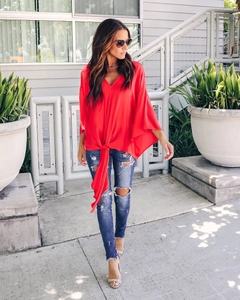 Outdoor street style view of women's red V-neck chiffon top with stylish front tie knot