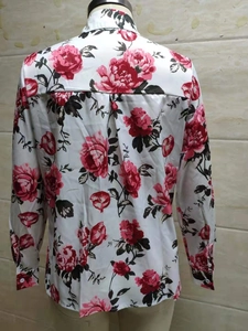 Détail de chemisier blanc à manches longues avec pli au dos et motif floral rose