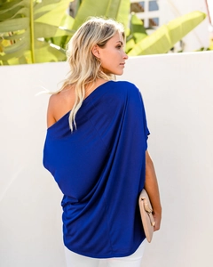 Detail of royal blue one shoulder top showing asymmetric cut and draped loose fit fabric