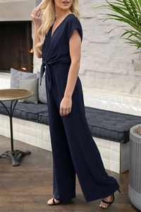 Detail view of navy blue V-neck jumpsuit with waist tie and wide-leg trousers fit