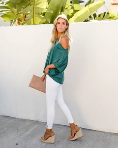 Detail of off-shoulder dark teal tunic paired with white ripped jeans and wedge sandals