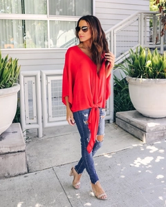 Detail of red V-neck chiffon blouse featuring front tie knot and flutter sleeves
