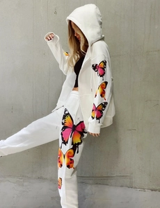 Detailed side view of ivory tracksuit showing vibrant butterfly prints and ribbed cuffs