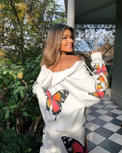 Detail of white hooded tracksuit featuring vibrant orange butterfly prints on sleeve and back