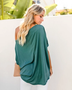 Outdoor side view of dark green one-shoulder T-shirt with loose fit and draping fabric