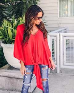 Detail of red deep V-neck blouse with soft textured fabric and waist tie design