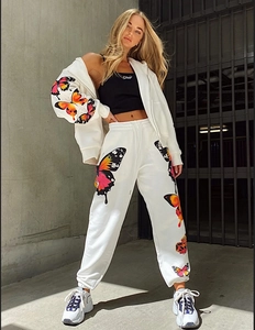 Detail of white cotton tracksuit featuring colorful butterfly prints and ribbed ankle cuffs
